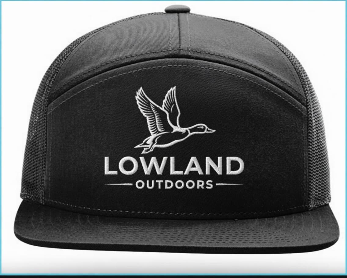 Black trucker hat with white embroidered flying duck and Lowland Outdoors brand logo.